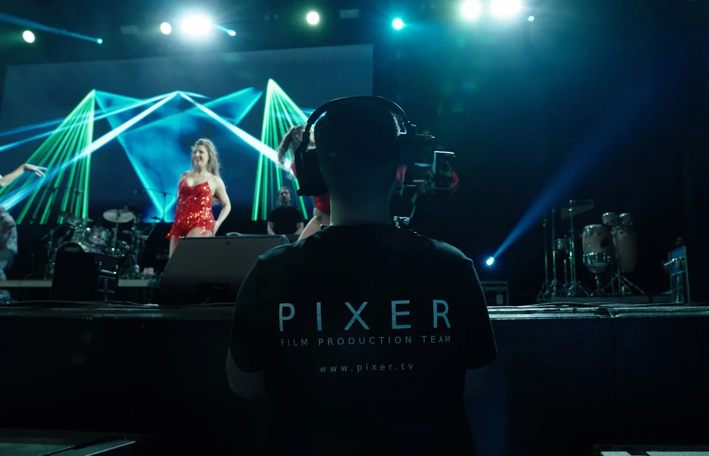 Pixer Filmproduktionsteam filmt ein Live-Konzert mit grüner geometrischer Lasershow auf der Bühne