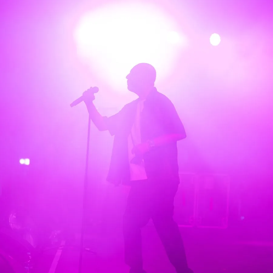Silhouette eines Performers auf der Bühne mit intensivem violettem Licht, fotografiert von Pixer