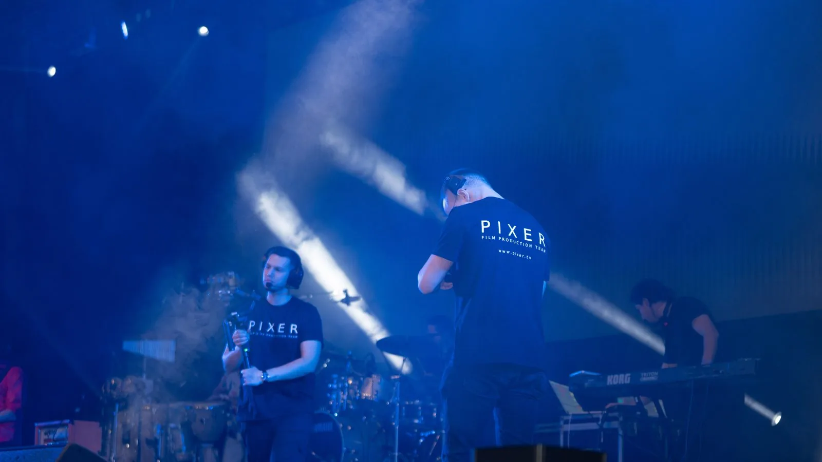 Pixer Filmteam auf der Bühne während eines Live-Konzerts mit dramatischer blauer Bühnenbeleuchtung